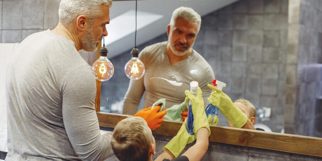 Photo of a dad and son. The dad is teaching the son cleaning habits to boost the mood